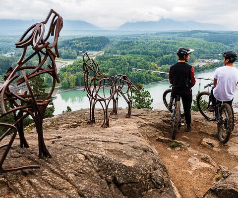 Heiko Krause and Wade Foster (right) stop for a moment to take in the view of the Skeena River and surrounding mountains in Terrace before continuing their ride. Keeping them company is a set of howling wolves created by local artist Steve Rogers as part of an initiative to blend artistic installations with trails along the Highway 16 corridor in northern B.C.